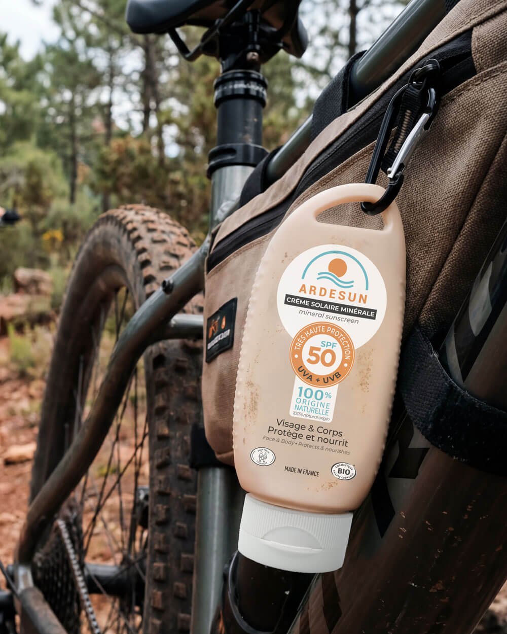 Crème solaire minérale SPF 50 ARDESUN fixée sur un vélo en forêt, protection solaire pour activité sportive